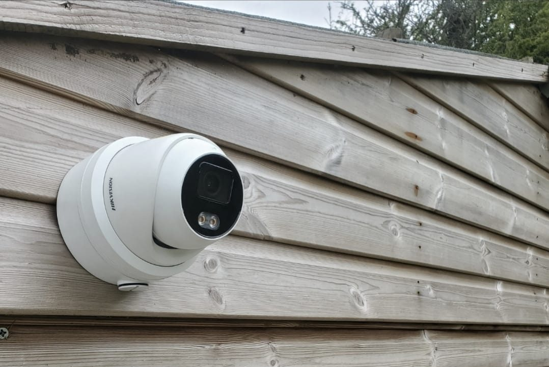 White Hikvision turret camera mounted on a timber outbuilding